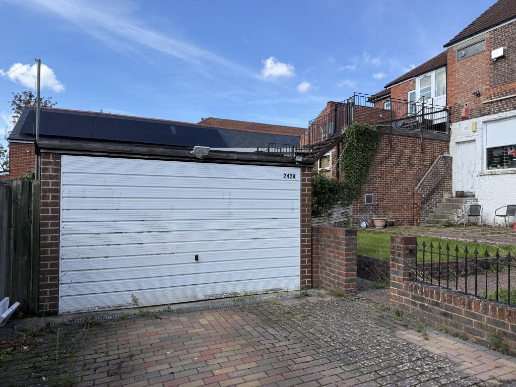 Lot: 128 - TWO-BEDROOM FLAT WITH GARAGE IN NEED OF IMPROVEMENT - Garage with white up and over style door